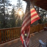 Flag over a log house deck, at sunset in Montana